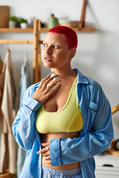 A young woman at home wears a bright yellow top and relaxed clothes, deep in thought. — Stock Photo
