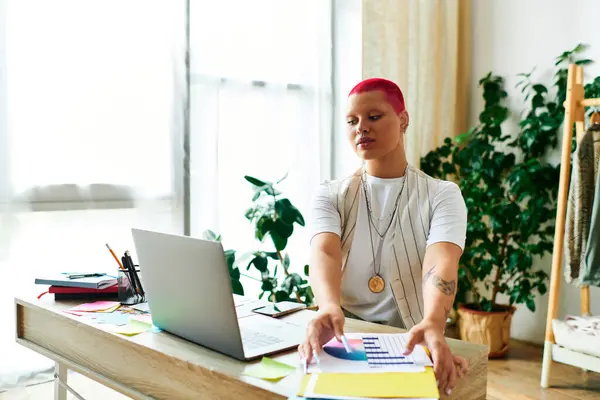 A young woman with a vibrant hairstyle works on projects at her plant filled home workspace. — Stock Photo