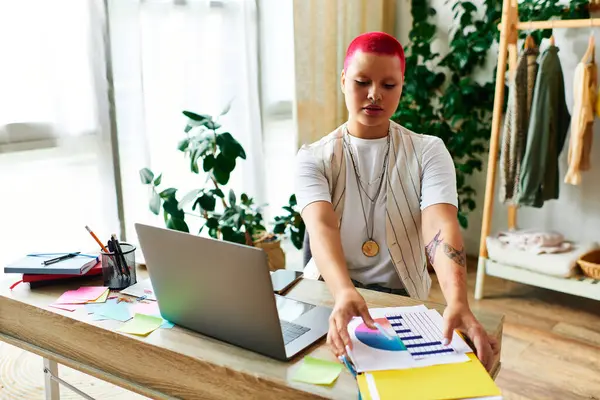 A young woman meticulously organizes colorful documents while seated at her home desk. — Stock Photo