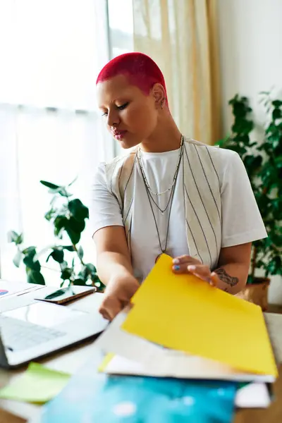 The woman sorts through colorful folders while seated at her home desk, focused and productive. — Stock Photo