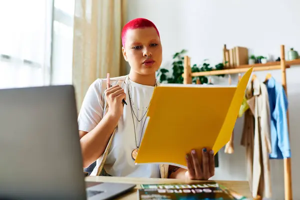 A young woman thoughtfully examines vibrant papers while seated at her home desk. — Stock Photo