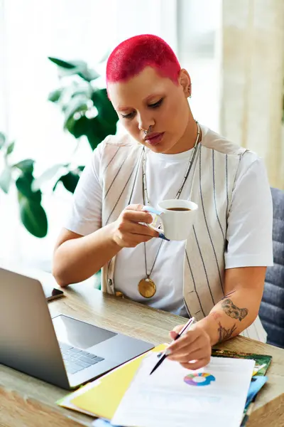 A young woman sips coffee at her desk while working on her laptop in a cozy home. — Stock Photo