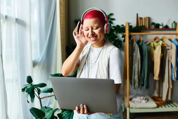The young woman connects online, smiling with joy while surrounded by indoor greenery. — Stock Photo