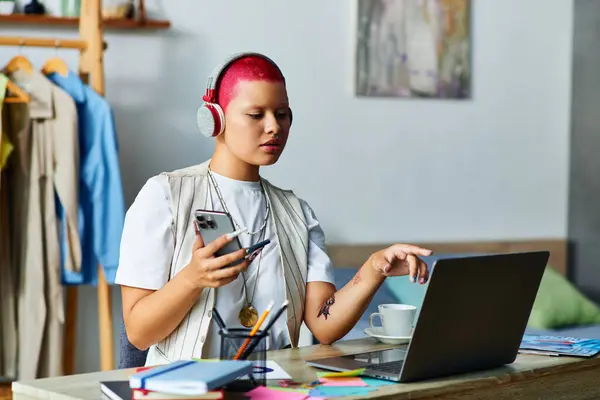 A young woman with vibrant pink hair engages with her laptop while multitasking at home. — Stock Photo