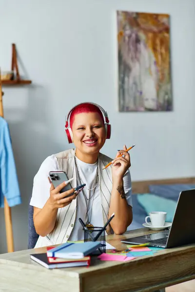 This young woman enjoys her creative time at home, balancing her phone and laptop while smiling. — Stock Photo