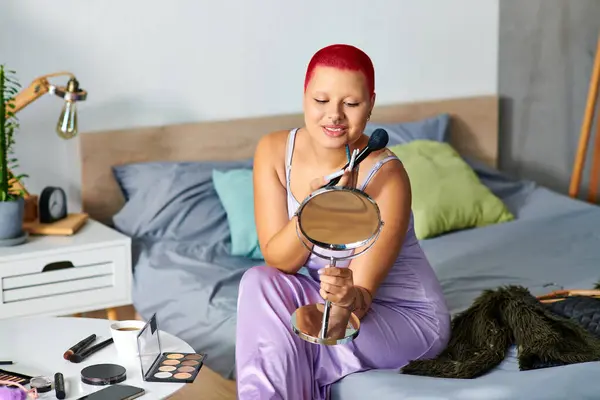 Eine junge Frau mit lebendigem Haar lächelt, als sie ihr Make-up in einer ruhigen Schlafzimmeratmosphäre vorbereitet. — Stockfoto