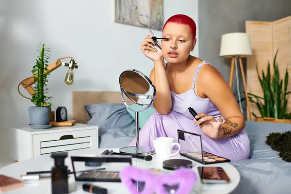 A young woman sits thoughtfully, enhancing her look with makeup in a stylish, serene bedroom. — Stock Photo