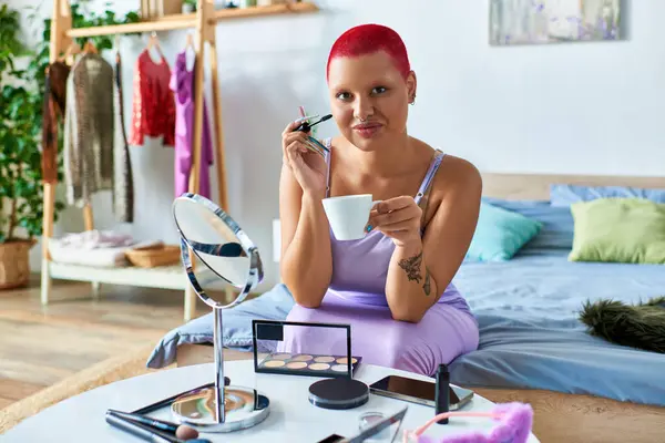 A young woman relaxes at home, sipping coffee and preparing her makeup in a vibrant space. — Stock Photo