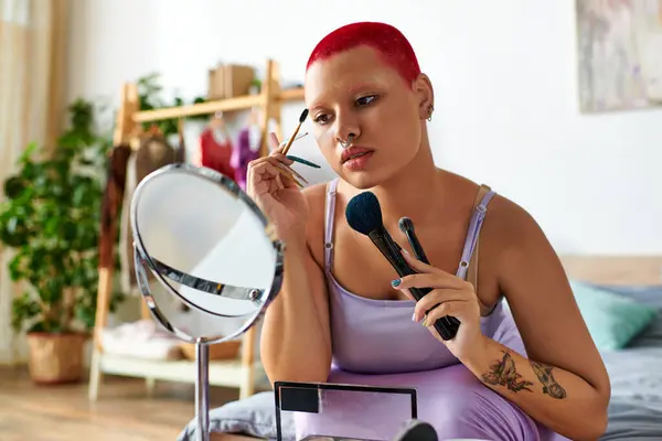 At home, a young woman perfectly applies her makeup while gazing into a mirror, showcasing style. — Stock Photo