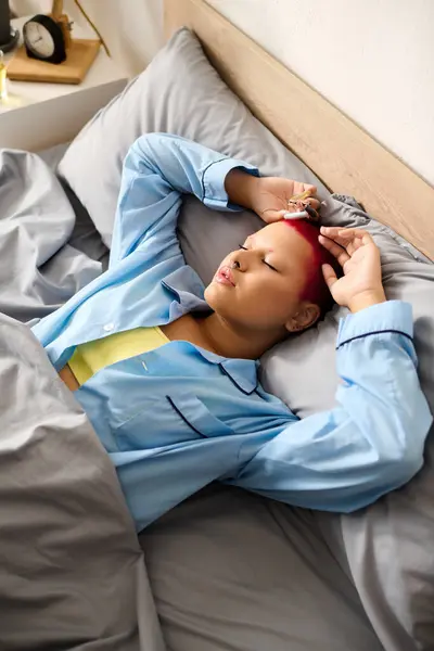 Eine junge Frau liegt im Bett und genießt einen ruhigen Morgen, mit entspanntem Gesichtsausdruck und hellen Haaren. — Stockfoto