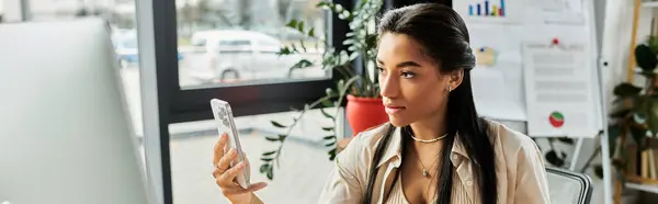 A young woman interacts with her smartphone, immersed in her office vibrant ambiance. — Stock Photo