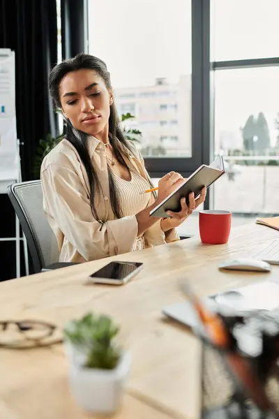 A young woman engages in creative thinking while taking notes in a bright, modern office space. — Stock Photo