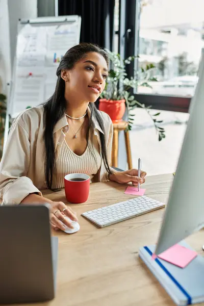 Una giovane donna si impegna in un lavoro premuroso alla sua scrivania mentre si gode una tazza di caffè. — Foto stock