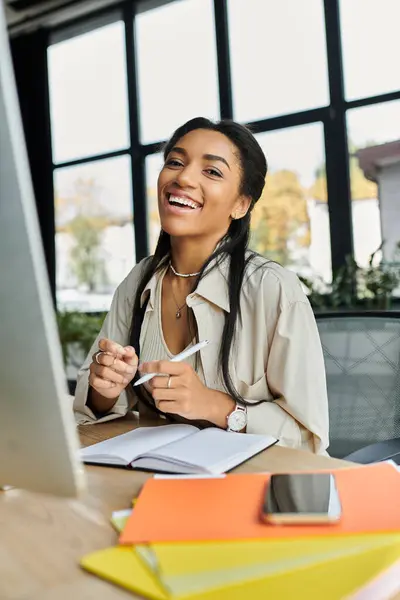 A joyful young woman works at her desk, illuminated by bright natural light. — Stock Photo