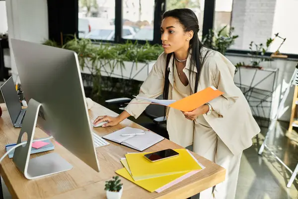 Una giovane donna concentrata organizza documenti mentre lavora alla sua elegante scrivania. — Foto stock