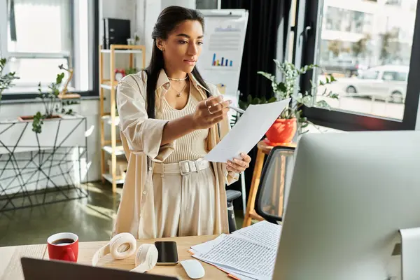 A confident woman analyzes important papers while standing in a stylish office space. — Stock Photo