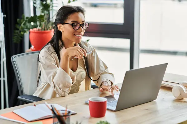 A confident young woman engages with her laptop, surrounded by a bright, inspiring workspace. — Stock Photo