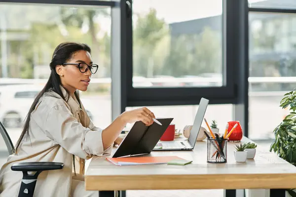 A professional woman engages with her documents while working in a bright office setting. — Stock Photo