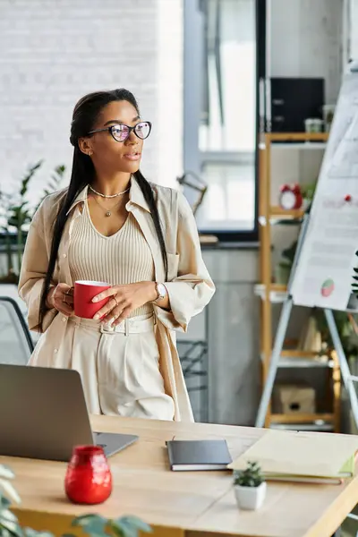 A vibrant young woman reflects thoughtfully while holding a coffee cup in her office space. — Stock Photo