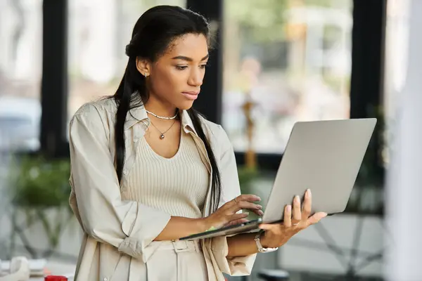 A focused woman engages with her laptop, immersed in work at a stylish office space. — Stock Photo