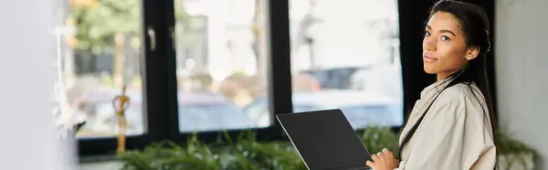 In a contemporary workspace, a young woman engages with her laptop, showcasing her focus. — Stock Photo