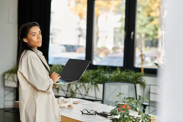 Eine junge Fachfrau greift zu ihrem Laptop und genießt die ruhige Büroumgebung. — Stockfoto