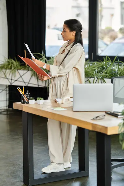 The woman stands confidently, organizing her files amidst a vibrant office atmosphere. — Stock Photo