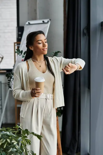 Une jeune femme élégante vérifie l'heure tout en tenant son café. — Photo de stock