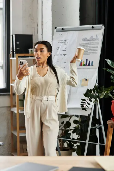 The young woman passionately shares ideas while balancing coffee and her phone in an office. — Stock Photo