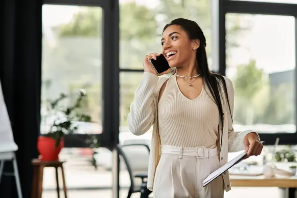 A young woman engages in a cheerful conversation on her mobile device, dressed for success. — Stock Photo