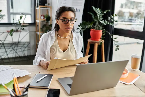 A young woman in stylish attire reviews important documents at her desk, deep in concentration. — Stock Photo