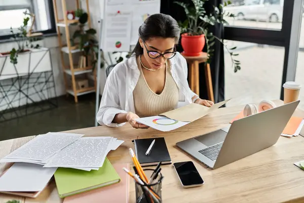 A young, vibrant woman is focusing intently on her work amid a creative office setting. — Stock Photo