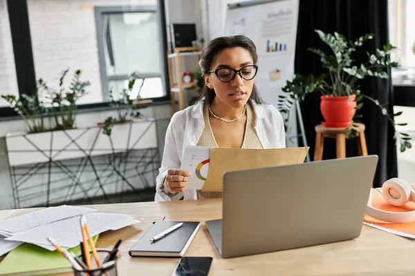 A young professional reviews documents and data while engaged in her work at a stylish office. — Stock Photo