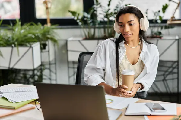 A confident young woman sips coffee during an online meeting in her stylish office. — Stock Photo