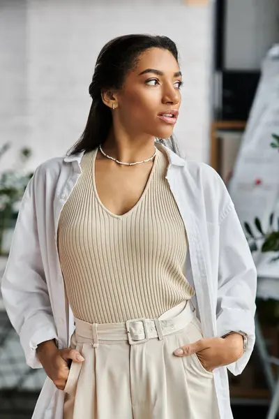 Une jeune et belle femme se tient confiante dans un bureau, incarnant professionnalisme et élégance. — Photo de stock