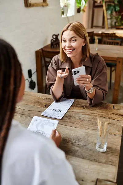 A smiling woman with braided hair engages warmly with her partner at a cafe, creating a lively atmosphere. — Stock Photo