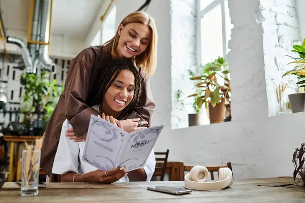 A smiling African American woman in braids enjoys a tender moment with her girlfriend at a quaint cafe — Stock Photo