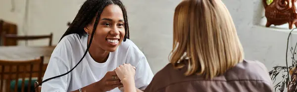 Two women enjoy a warm moment at a cafe, exchanging loving smiles and laughter over coffee. — Stock Photo