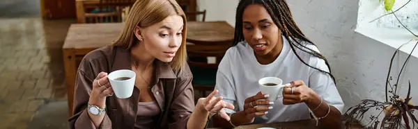A joyful moment unfolds as two women share laughter and coffee at a quaint cafe table, immersed in conversation. — Stock Photo