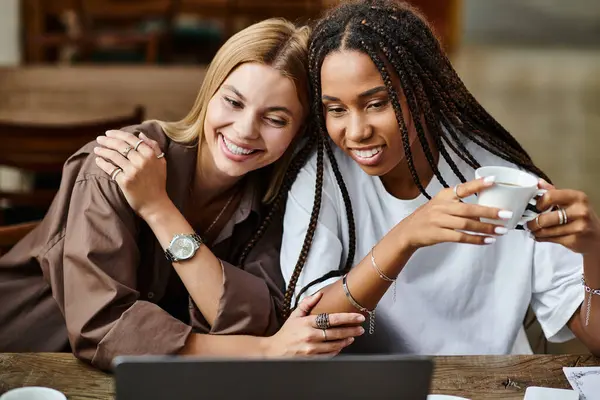 Eine lächelnde Afroamerikanerin mit Zöpfen teilt einen warmen Moment mit ihrer Freundin in einem Café — Stockfoto