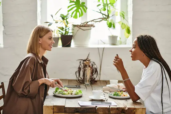 A vibrant and loving multicultural couple enjoys a meal together in a charming cafe, sharing smiles and stories. — Stock Photo