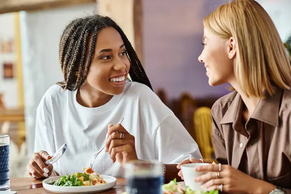 A joyful moment of two women sharing a meal at a cafe, surrounded by laughter and warmth. — Stock Photo
