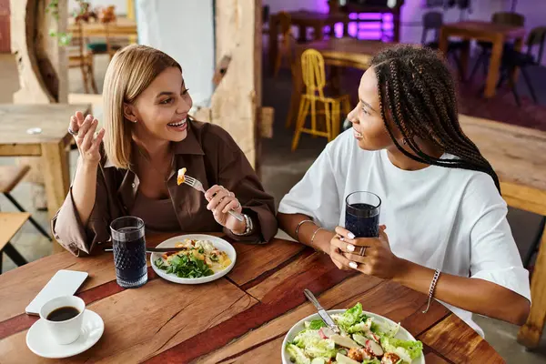 A relaxed atmosphere as a joyful couple shares laughter and delicious food in a cozy cafe. — Stock Photo