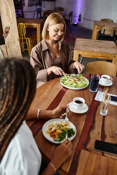 A joyful moment unfolds as an African American woman shares a lunch date at a cafe with her girlfriend. — Stock Photo