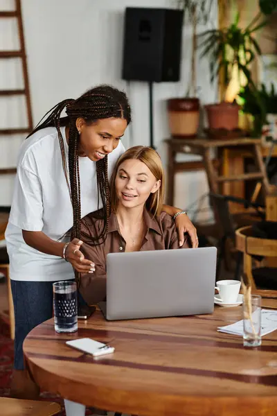 In a charming cafe, a joyful African American woman shares a smile with her girlfriend while they work together. — Stock Photo