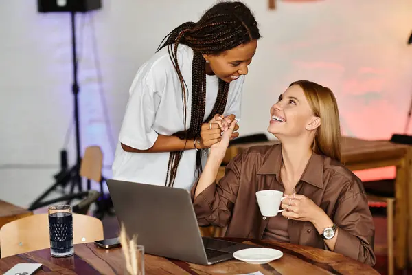 Inside a friendly cafe, an African American woman shares a warm smile with her girlfriend while enjoying coffee. — Stock Photo