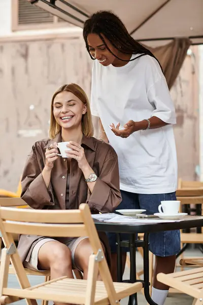 Ein fröhliches multiethnisches Paar teilt einen Moment in einem Café, während man bei einem Drink fröhlich lächelt. — Stockfoto