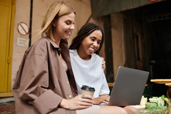 A multiethnic couple is enjoying a delightful cafe visit, sharing smiles and laughter while working together. — Stock Photo