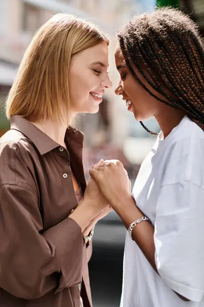 Two women share a tender moment, smiling and holding hands as they gaze into each others eyes. — Stock Photo