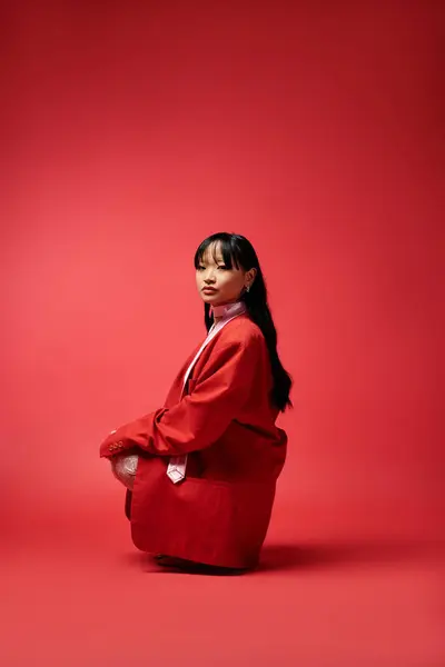 Elegantemente vestida em um conjunto vermelho, a jovem faz uma pose equilibrada, mostrando sua beleza. — Fotografia de Stock